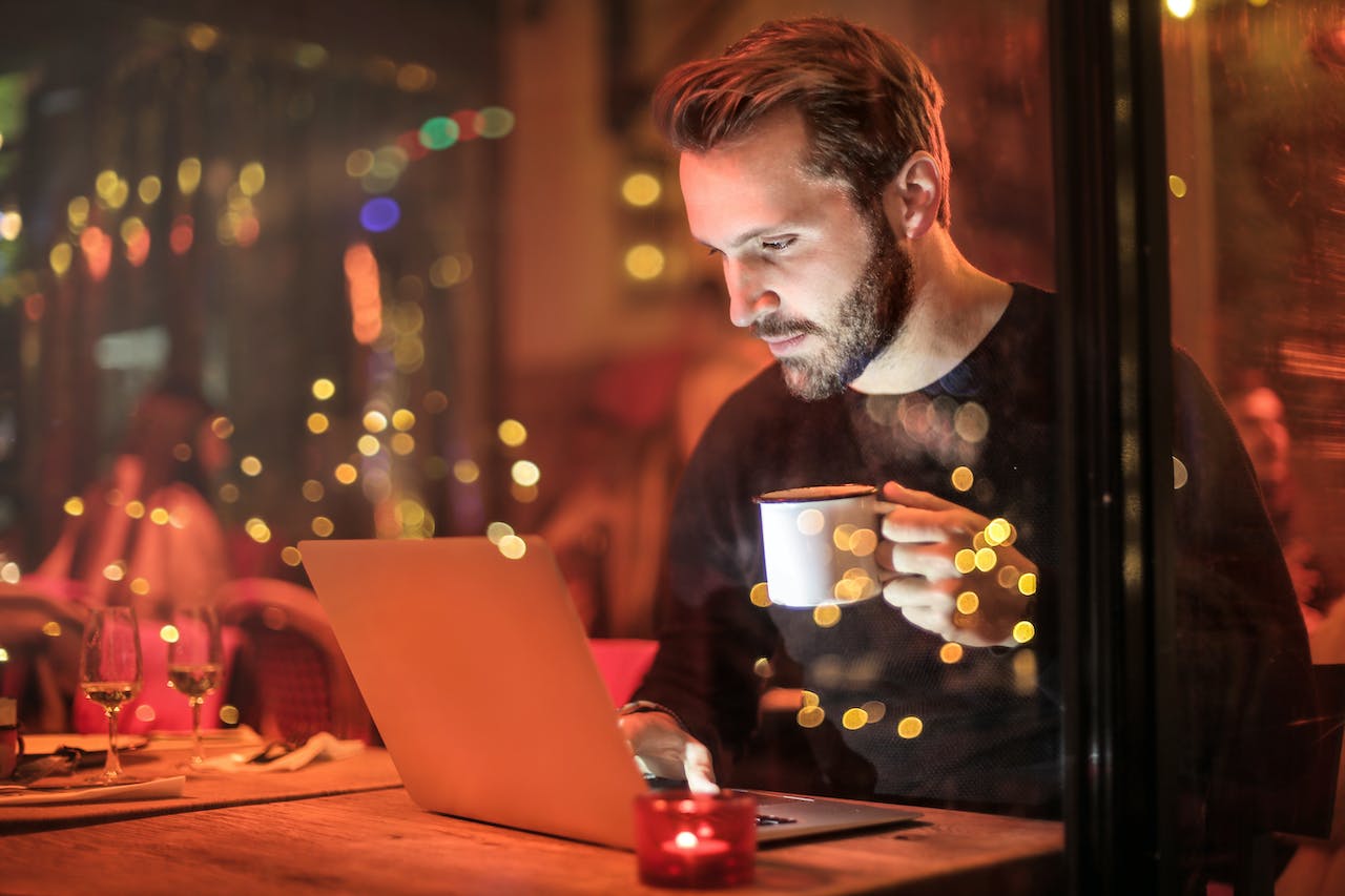 Ein Mann sitzt in einem Caffee und schaut auf seinen Laptop